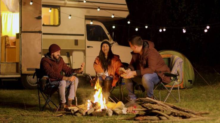 Groupe d'amis proches riant ensemble autour d'un feu de camp-Camping In The Rain