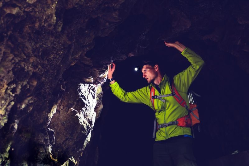 Homme explorant la grotte sombre | Lampes frontales