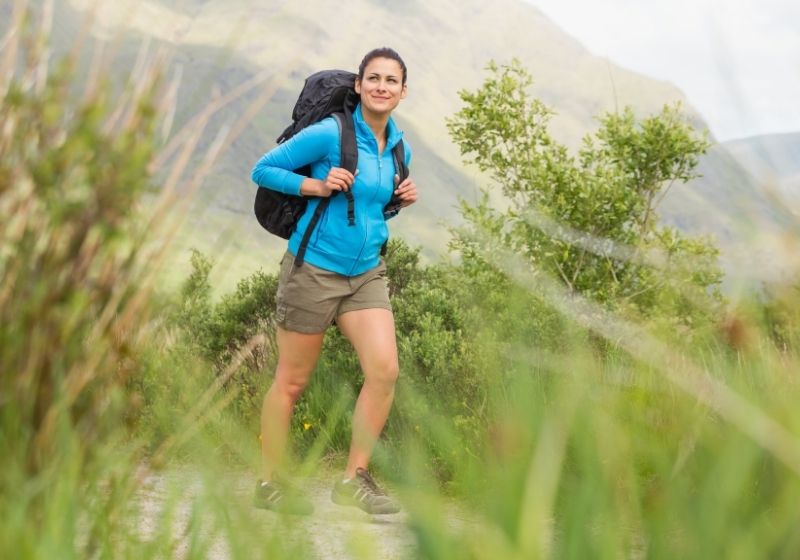 Randonneuse avec sac à dos marchant et souriant | Liste d'équipement de Wanderlust fait maison | XX choses que vous devriez avoir dans votre liste d'équipement de sentier des Appalaches