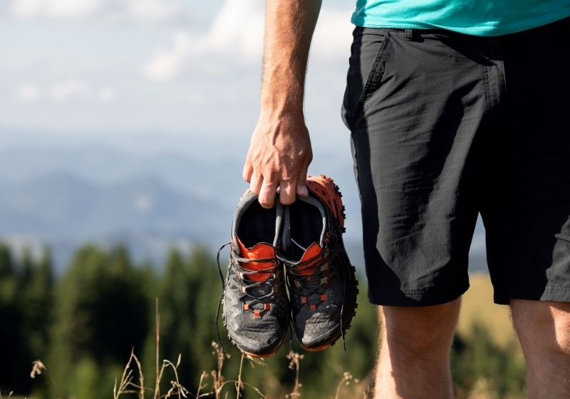 Homme tenant des baskets sur les montagnes | Liste d'équipement de Wanderlust fait maison | XX choses que vous devriez avoir dans votre liste d'équipement de sentier des Appalaches