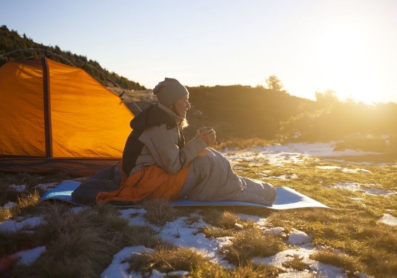 Fille assise dans un sac de couchage et buvant une boisson chaude | Liste d'équipement de Wanderlust fait maison | XX choses que vous devriez avoir dans votre liste d'équipement de sentier des Appalaches
