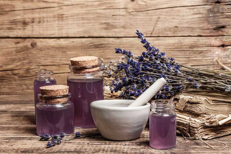 Fleurs de lavande séchées dans un mortier et un pilon avec une bouteille d'huile essentielle de lavande | Répulsifs naturels contre les moustiques