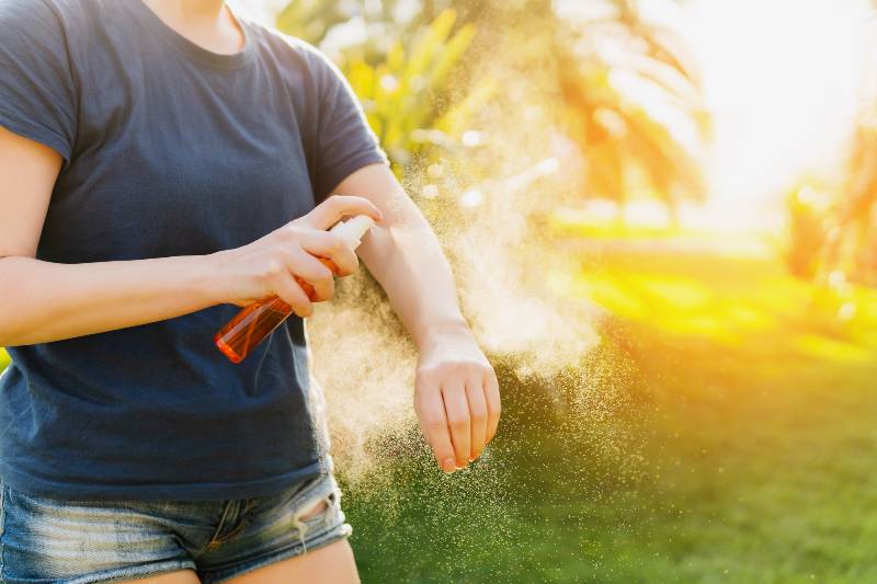 Femme appliquant un insectifuge avant une randonnée en forêt belle journée d'été | Répulsifs naturels contre les moustiques