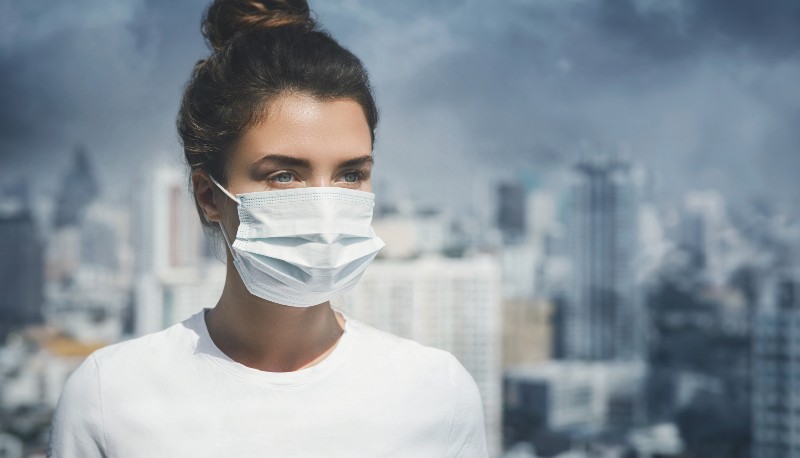 Femme portant un masque facial à cause de la pollution de l'air dans la ville | La pollution de l'air